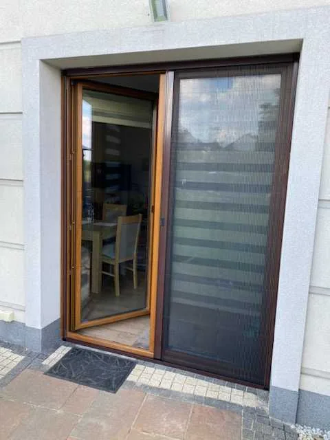 Moskitiera plisowana w profilu drewnopodobnym w realizacji na Śląsku - detal dopasowania profilu do stolarki