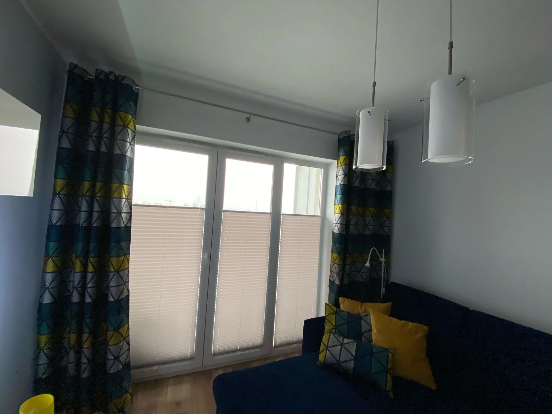 Plisy przy balkonowym przeszkleniu w realizacji na Śląsku - szerszy widok przeszklenia balkonowego z plisami w salonie