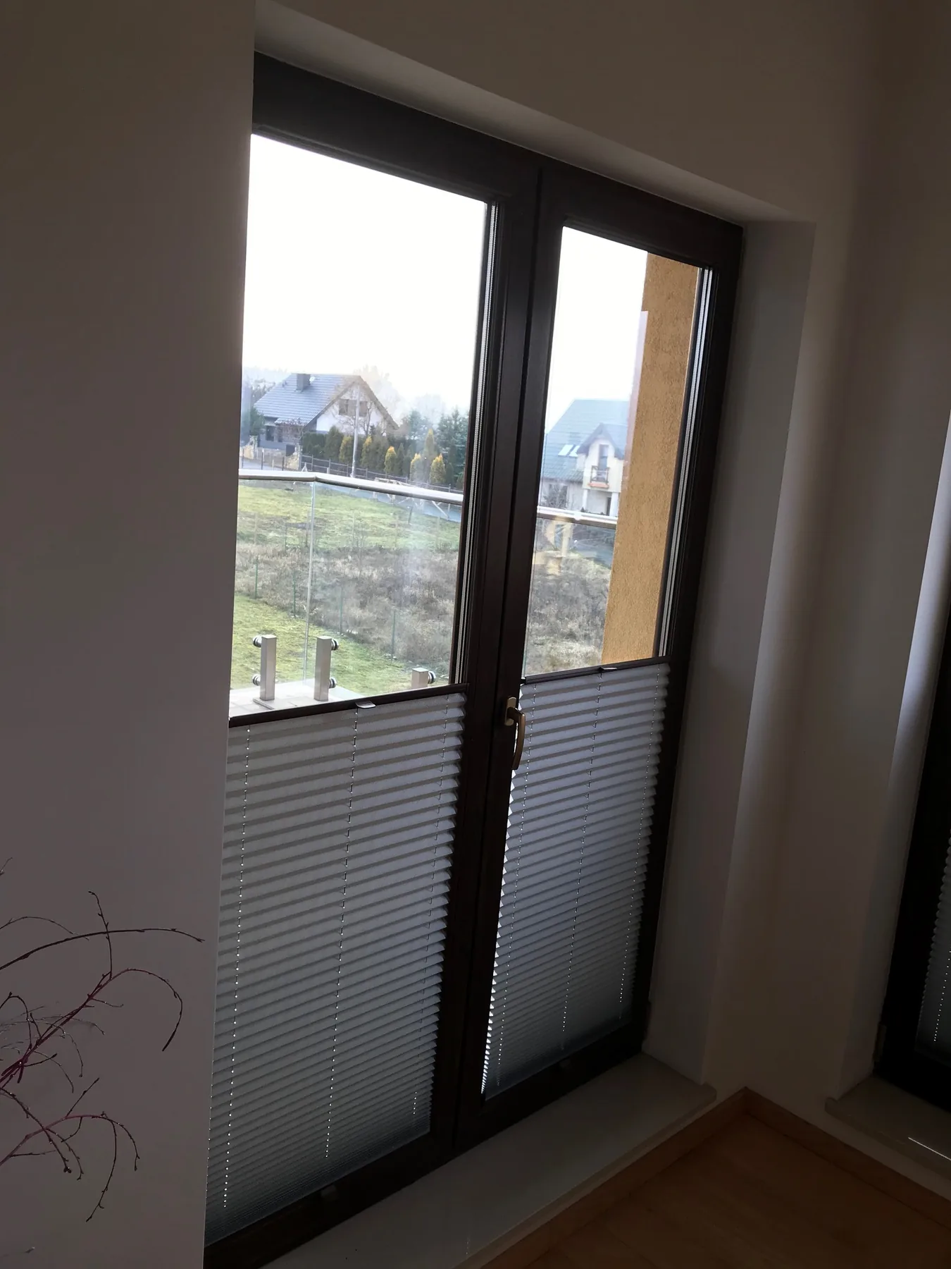 Plisy przy czarnej stolarce w realizacji na Śląsku - widok drzwi balkonowych w sypialni z plisami