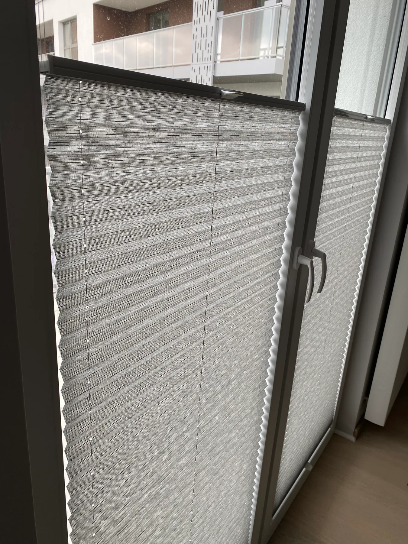Plisy w salonie z szerokim przeszkleniem w realizacji na Śląsku - detal faktury tkaniny przy białej ramie