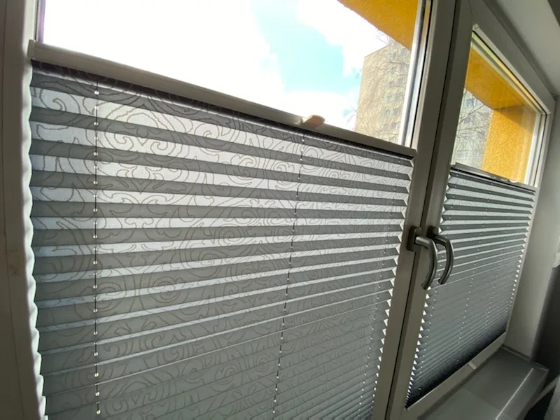 Plisy przy podwójnym oknie w szarej stolarce w realizacji na Śląsku - detal wzoru tkaniny i prowadzenia w szarej ramie