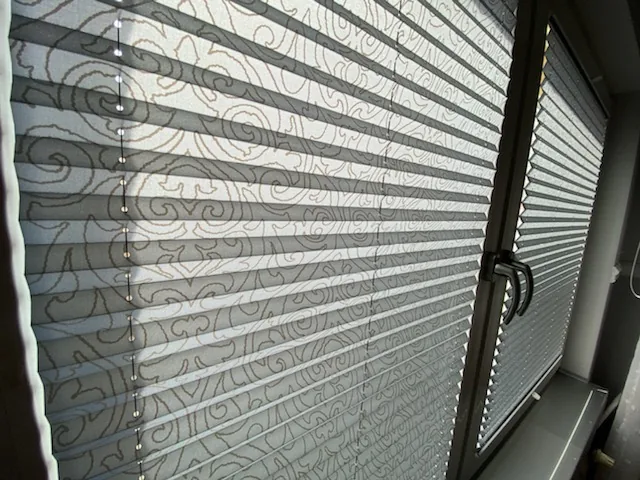 Plisy przy podwójnym oknie w szarej stolarce w realizacji na Śląsku - efekt końcowy po montażu w spokojnym wnętrzu