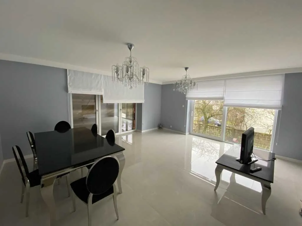 Rolety rzymskie w szarym wnętrzu w realizacji w Bytomiu - widok strefy dziennej z roletami rzymskimi