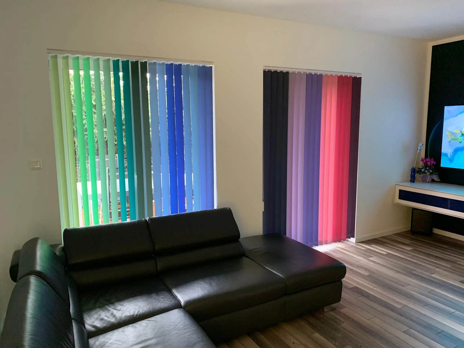 Żaluzje pionowe z kolorowymi lamelami w realizacji na Śląsku - szerszy widok salonu z dwoma dużymi przeszkleniami